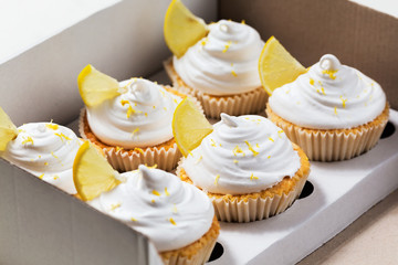 Lemon cupcakes with white cream, cupcake packaging, delivery box, selective focus, close up