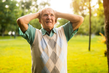 Man holding head in despair. Elderly guy outdoor. Burden of mistakes. Horrible things have happened.