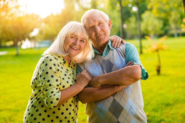 Senior woman hugs man. Couple looking at the camera. Hearts united by love. Support and trust are priceless.