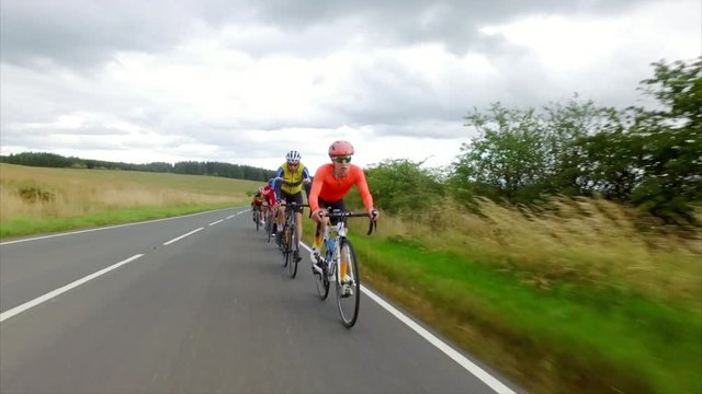 A group of cycling athletes out on a training ride on country roads in the UK countryside on an overcast day. 