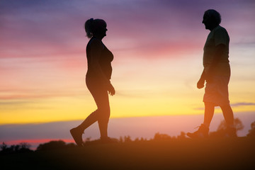 Fototapeta premium Couple walking towards each other. People on background of sunset. I've been looking for you. After years of being apart.