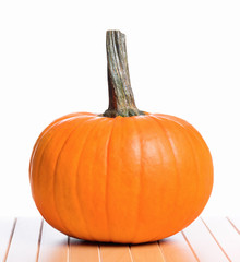 Fresh orange pumpkin on table, isolated on white background. Studio shot of a nice ornamental autumn pumpkin for Halloween.