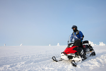 Fototapeta na wymiar Man driving snowmobile in Finland