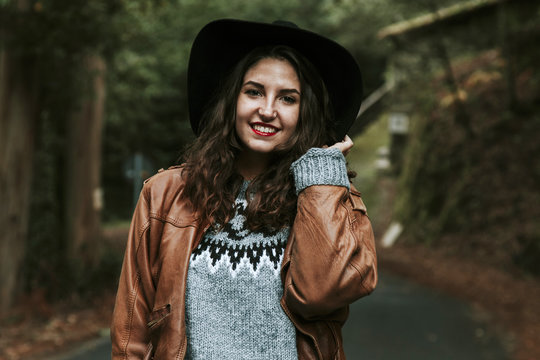 smiling girl with cowboy hat on forest road
