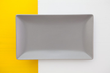 Empty gray ceramic dish on over white and yellow  background,