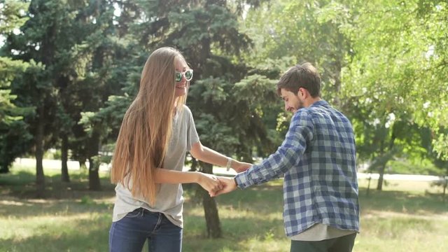 Happy couple whirls on hoverboards with holding hands. Wide shot