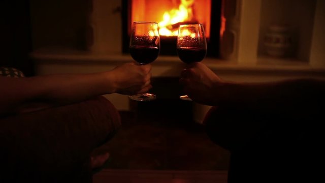 Romantic couple evening with glasses of wine in cozy home near the fireplace