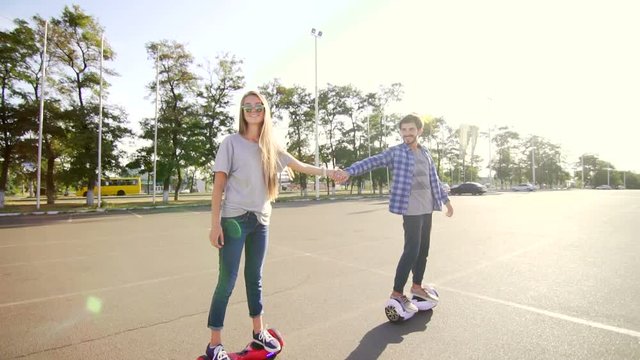 Modern young man and woman walking with Hoverboard. A new movement. Wide shot. Dual Wheel Self Balancing Electric Skateboard Smart