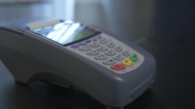 Contactless payment being made with a credit card over a terminal sitting on a retail store counter.