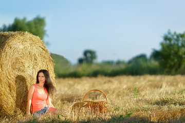 Girl sitting near a stack of straw