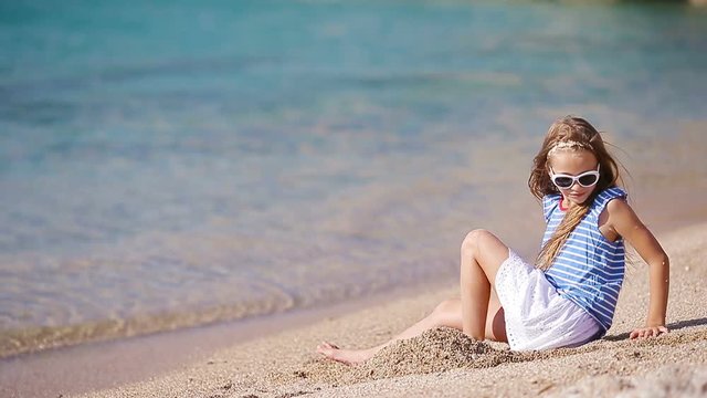 Adorable little girl have fun on the beach during vacation