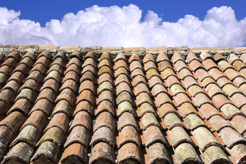 Old roof tiles, blue sky and clouds in the background