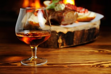 glass of cognac on the background  a meat dish