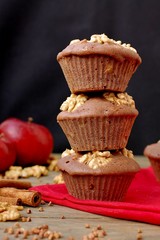 Gluten free muffins from buckwheat flour, apple, cinnamon and walnuts on red cloth on brown wooden table with black background