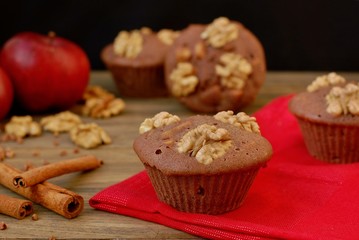 Gluten free muffins from buckwheat flour, apple, cinnamon and walnuts on red cloth on brown wooden table with black background