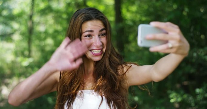 A woman surrounded by greenery you take pictures and talk to the camera and greets the people with whom it is to smart-phone