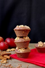 Gluten free muffins from buckwheat flour, apple, cinnamon and walnuts on red cloth on brown wooden table with black background