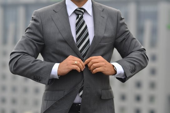 Handsome young businessman in classic suit is buttoning his jacket