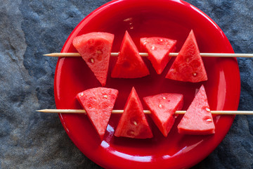 watermellon slices on skewers on a red plate