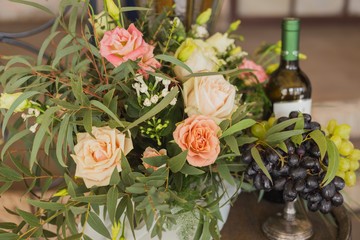 grapes on vase near flowers and bottle of vine