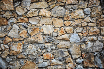 Stonework wall background with green and brown rough stones of d