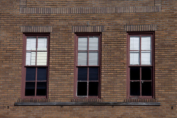 Three red rectangular windows on a large antique brick building