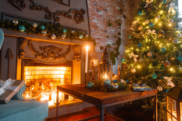 Christmas evening by candlelight. classic apartments with a white fireplace, decorated tree, sofa, large windows and chandelier.
