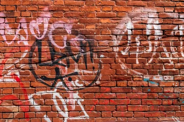 Papier Peint photo Graffiti mur de briques rouges avec des graffitis de différentes couleurs