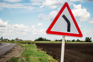 Traffic sign on a blurred background with clouds, field, road