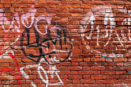 red brick wall with graffiti in different colors
