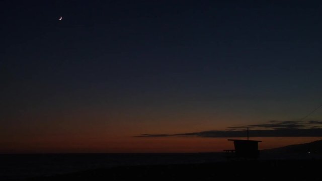 Beach sunset with moon an lifeguard tower, Santa Monica, California.