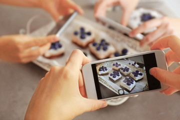 People taking photo of tasty cakes with blueberries