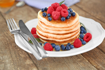 White plate full of tasty pancakes with berries