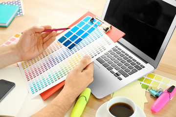 Fototapeta na wymiar Designer workplace. Hands holding clipboard with colour palette