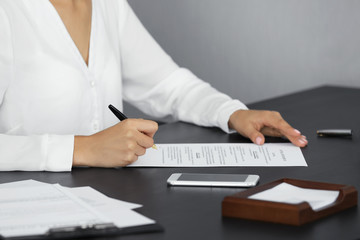 Woman signing important document in modern office