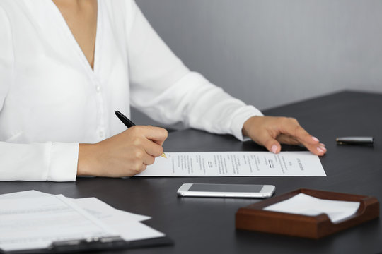 Woman signing important document in modern office