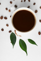 Cup of coffee with grains, green leaves and stain on white background, closeup