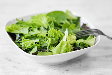 Fresh delicious salad on white wooden background, closeup
