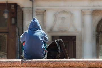 Man with sweatshirt and a black bag sitting alone
