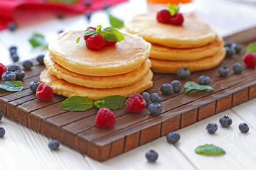 Tasty pancakes with berries on wooden table