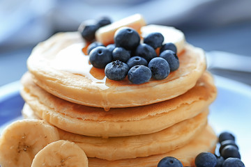 Plate with tasty pancakes and berries on blurred background, close up view