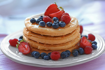 Plate with tasty pancakes and berries on wooden table, close up view