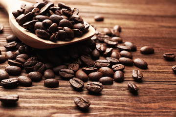 Wooden spoon and coffee beans on wooden background, close up view