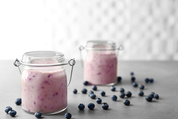 Mason jar with tasty smoothie and blueberries on kitchen table