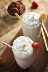 Delicious milkshakes with banana and strawberry on wooden table closeup