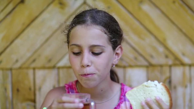 Girl eats white bread and drinks tea. Beautiful girl eats slice of bread and washes down tea