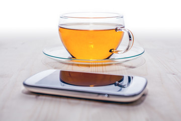 A Smartphone In Front Of A Cup Of Tea On A Wooden Board