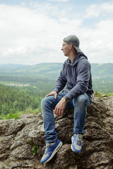 Male resting and enjoying the mountain sitting on rock