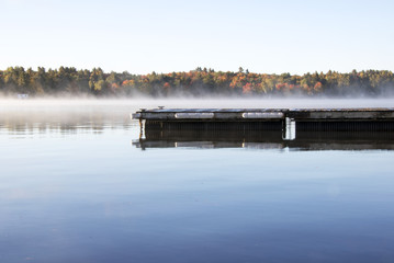 Cottage Dock over the Lake water on a misty morning on a Fall Day