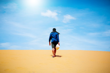 man walking through desert sand dunes